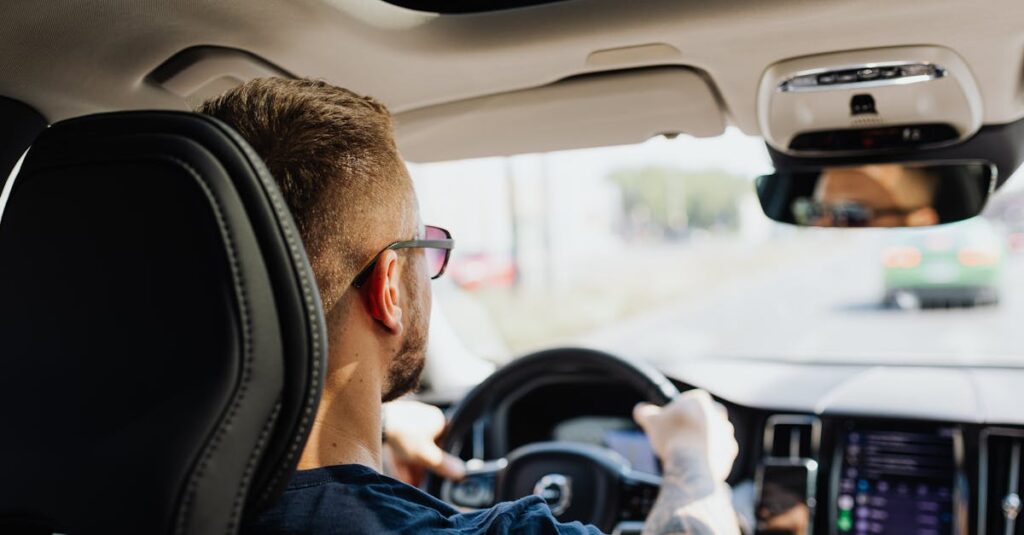 Rear view of a man driving a car with focus on interior details and steering.